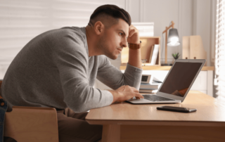 Man with Poor Posture Using Laptop at Table Indoors